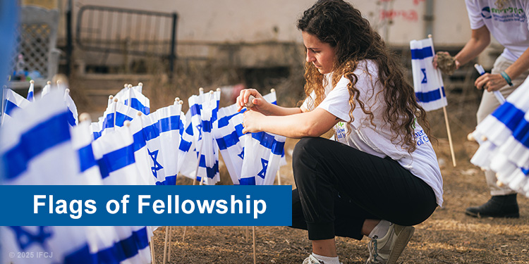 Young girl kneeling down to plant an Israeli flag in the ground.